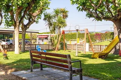 a park with a bench and playground equipment at Residencial Costamar next Bcn, 50m beach with swimming pool in Cabrera de Mar