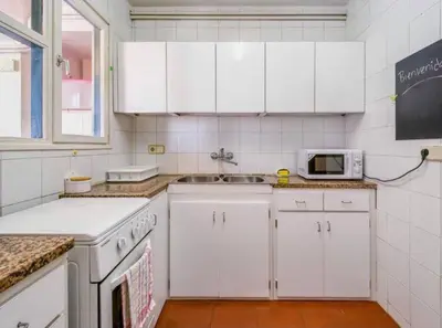 a kitchen with white cabinets and a sink and a microwave at Can Mabi, 30' Bcn next beach in Vilassar de Mar