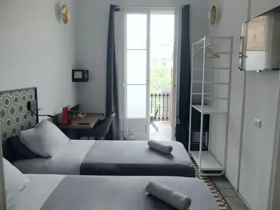 a bedroom with two beds and a desk and a window at Fabrizzio's Petit in Barcelona