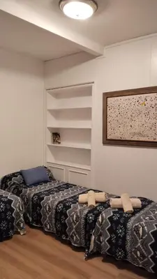 a room with two beds and a wall with shelves at Atico Soleado Vistas panoramicas in Hospitalet de Llobregat