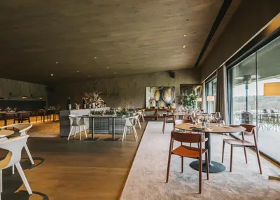 a restaurant with wooden ceilings and tables and chairs at Les Cabanes de l'Oller del Mas in Manresa