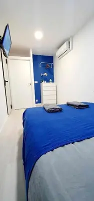 a bedroom with a blue bed and a tv at Hostal Urban Basic in Hospitalet de Llobregat
