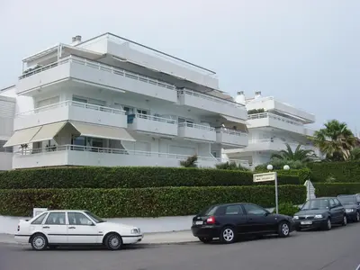 a white building with cars parked in front of it at Apartamentos Sunway Talaia in Sitges