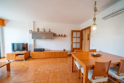 a dining room with a table and a tv at HomeHolidaysRentals Adara in Pineda de Mar