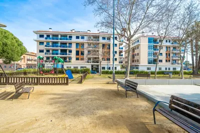 a park with benches and a playground in front of a building at HomeHolidaysRentals Adara in Pineda de Mar