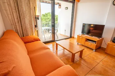 a living room with a couch and a tv and a table at HomeHolidaysRentals Adara in Pineda de Mar