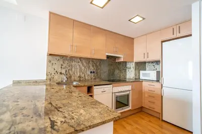 a kitchen with wooden cabinets and a marble counter top at HomeHolidaysRentals Marella - Costa Barcelona in Pineda de Mar