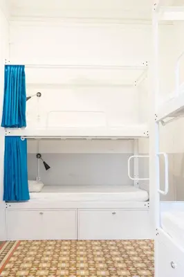 a room with white bunk beds and blue curtains at Soul Backpackers Barcelona in Barcelona