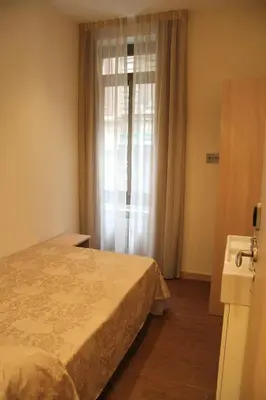 a bedroom with a bed and a window with curtains at Hostal Excellence in Barcelona