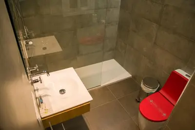 a bathroom with a shower and a sink and a red stool at Flat Barcelona in Barcelona