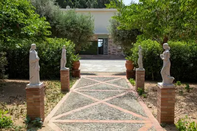 a garden with statues in front of a house at Villa Can Bagués in Mataró
