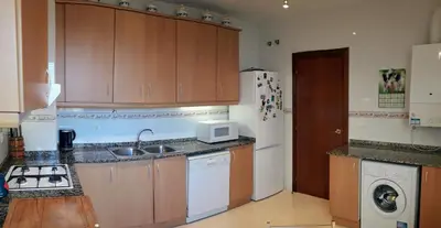 a kitchen with wooden cabinets and a white refrigerator at Casa Ana -Cubelles in Cubelles