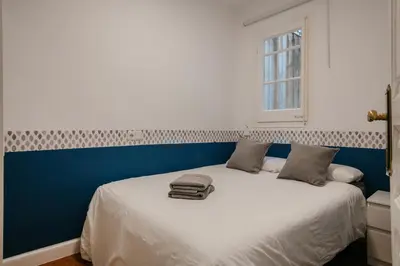 a bedroom with a white bed with a blue wall at Nice Apartment in Barcelona