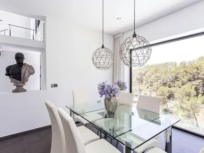 a dining room with a glass table and white chairs at Architect modern design villa in Sitges Hills in Olivella