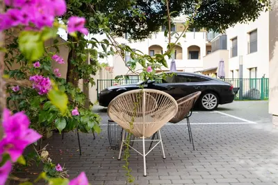 a table and chairs on a sidewalk with a black car at Castell Beach Aparthotel in Castelldefels
