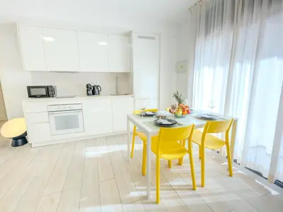 a kitchen with a table and yellow chairs in a room at Castell Beach Aparthotel in Castelldefels