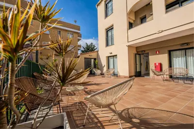 a patio with chairs and tables in a building at Castell Beach Aparthotel in Castelldefels