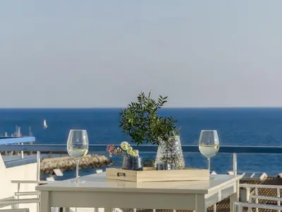 a table with two wine glasses and flowers on a balcony at Sitges Spaces Sea View Paradise- 2 Bedrooms, 2 Bathrooms, Terrace, Amazing Sea Views in Sitges