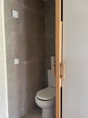 a bathroom with a toilet and a tiled wall at Les Suites in Santa María de Palautordera