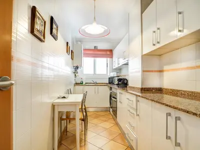 a kitchen with white cabinets and a small table at Linda Vista Oasis Penthouse by Hello Homes Sitges in Sitges