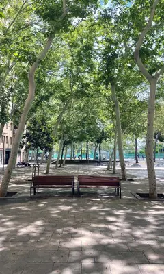 two park benches sitting in a park with trees at Hotel BESTPRICE Diagonal in Barcelona