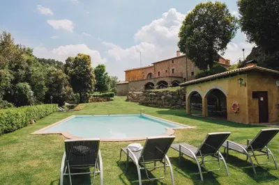 a pool in a yard with chairs and a building at La Caseta del Munt in Castelltersol