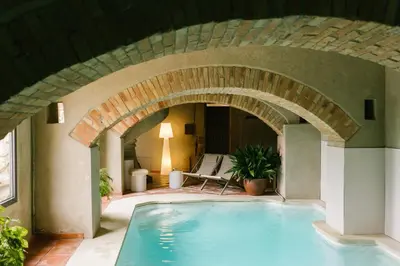 a swimming pool in a building with an archway at La Caseta del Munt in Castelltersol