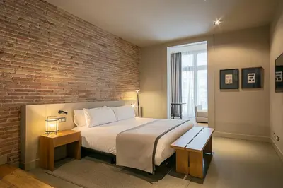 a bedroom with a large bed and a brick wall at Colectia Stays Pau Claris in Barcelona