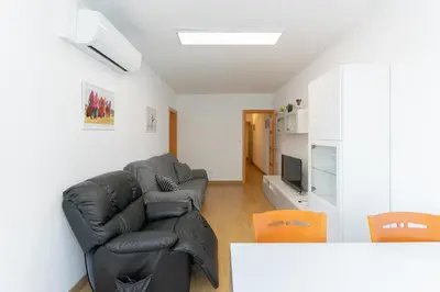 a living room with a black leather couch and orange chairs at Cadillac Check-in flexible-Bien comunicado-cerca Barcelona in Cornellà de Llobregat