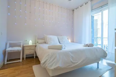 a white bedroom with a large bed and a window at HomeHolidaysRentals Plume - Costa Barcelona in Pineda de Mar