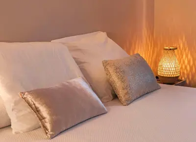 a white bed with white pillows and a lamp at PassiveRooms in Vilanova i la Geltrú