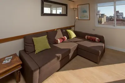 a living room with a brown couch and a table at Gaudi penthouse with terrace views in Barcelona