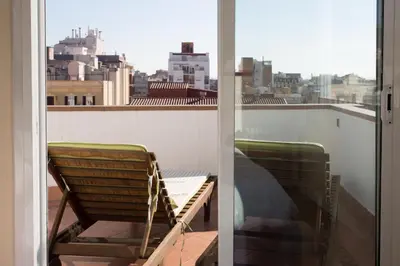 a chair on a balcony with a view of a city at Gaudi penthouse with terrace views in Barcelona