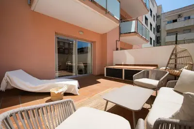a balcony with chairs and tables on a building at Aparthotel Centric in Castelldefels