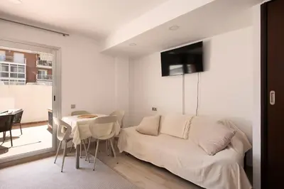 a white living room with a bed and a table at Aparthotel Centric in Castelldefels