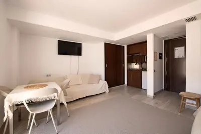 a bedroom with a bed and a table and a kitchen at Aparthotel Centric in Castelldefels
