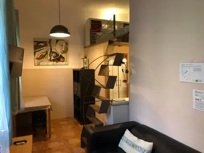 a living room with a black couch and a staircase at Estudio Finestrelles Barcelona in Esplugues de Llobregat