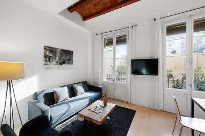 a living room with a blue couch and a tv at AB Gran de Gràcia in Barcelona