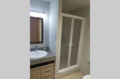 a bathroom with a shower and a sink and a mirror at Apartamento para 5 personas frente al mar con piscina y parking in Cubelles