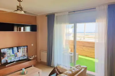 a living room with a couch and a large window at Apartamento para 5 personas frente al mar con piscina y parking in Cubelles