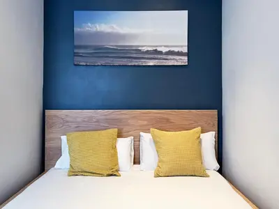a bed with yellow pillows and a blue wall at Stay U-nique Apartments Travessera in Barcelona