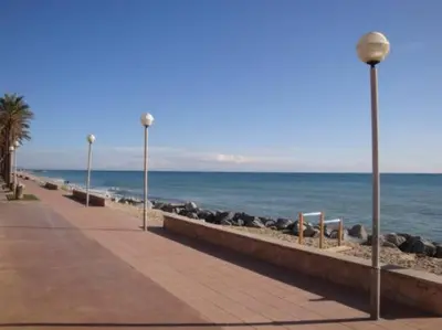 a sidewalk next to the ocean with a beach and street lights at CASA la PAU in Vilassar de Mar