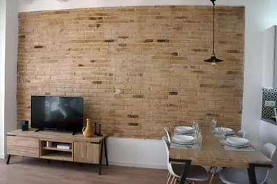 a dining room with a table with a tv and a brick wall at Barcelona Industrial Style Apartment in Hospitalet de Llobregat