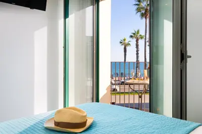 a hat sitting on a bed with a view of the beach at Kronos on the beach Suite 2 in Barcelona