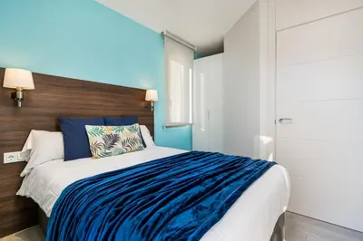 a bedroom with a bed with blue and white sheets at Kronos on the beach Suite 4 in Barcelona