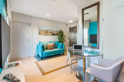 a living room with a blue couch and a glass table at Kronos on the beach Suite 4 in Barcelona