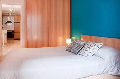 a bedroom with a white bed with a blue wall at Bbarcelonapartment Acogedor, tranquilo con Balcón in Barcelona