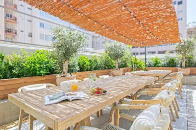 a row of wooden tables and chairs on a roof at Olivia Barcelona in Barcelona