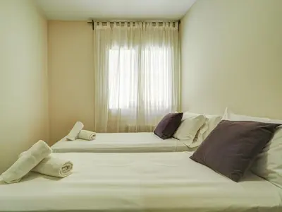 two beds in a room with a window at Beach Matucana Apartment by Hello Homes Sitges in Sitges