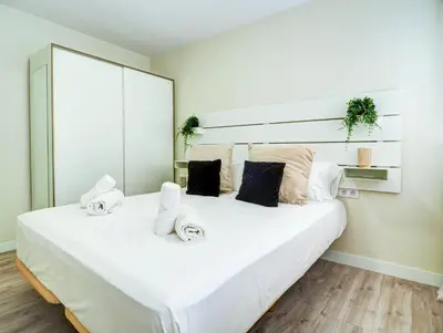 a bedroom with a large white bed with towels on it at Beach Matucana Apartment by Hello Homes Sitges in Sitges
